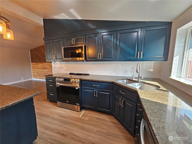 kitchen featuring lofted ceiling, stainless steel appliances, light wood finished floors, and a sink