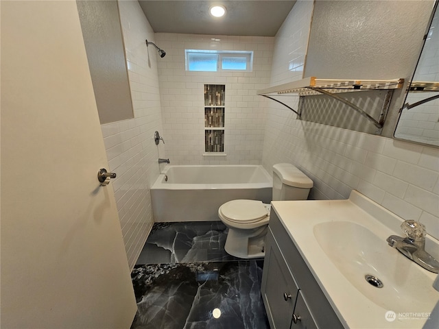 full bathroom featuring vanity, tile patterned floors, tiled shower / bath, tile walls, and toilet