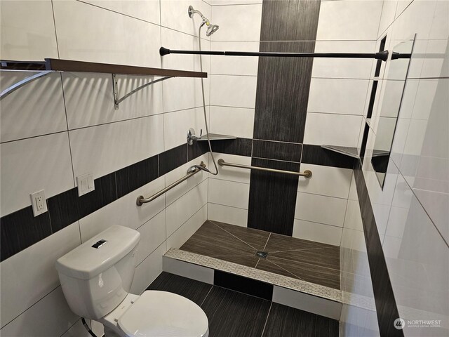 bathroom with tile walls, tiled shower, and toilet