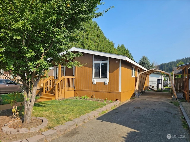 view of property exterior with a yard, a carport, and aphalt driveway