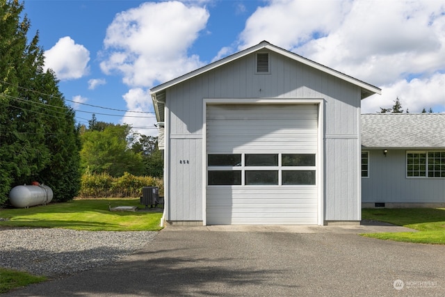 garage with a yard and central AC unit