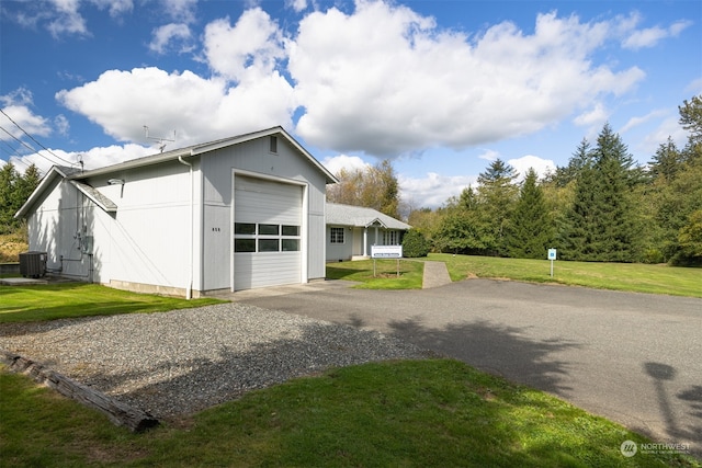 exterior space with central air condition unit, a front yard, and a garage