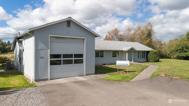 ranch-style house with central AC unit, a garage, a front lawn, and an outbuilding