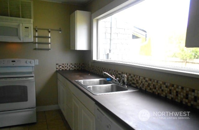 kitchen featuring sink, white appliances, and dark tile patterned flooring