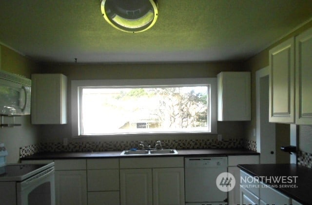 kitchen with white appliances, sink, and white cabinets