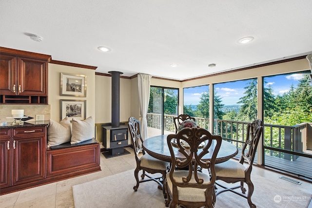 tiled dining area with a wood stove and ornamental molding