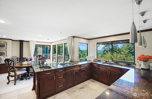 kitchen featuring stainless steel gas cooktop, sink, dark stone counters, and a healthy amount of sunlight