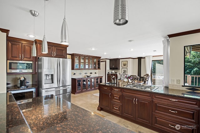 kitchen featuring dark stone countertops, tasteful backsplash, decorative light fixtures, and stainless steel appliances