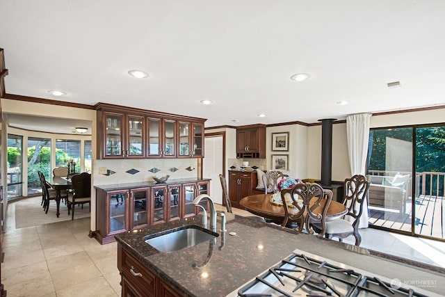 kitchen with ornamental molding, a wood stove, tasteful backsplash, and sink