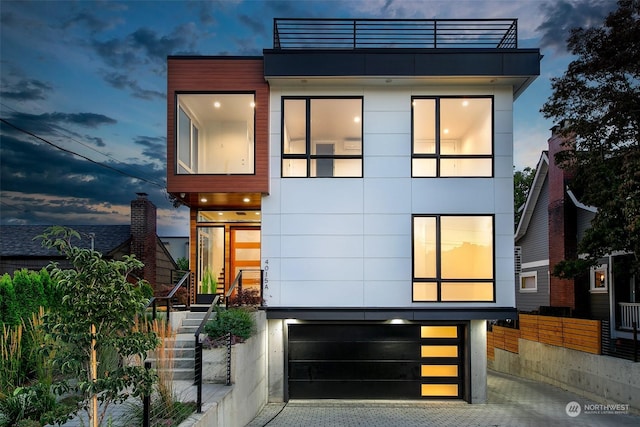 modern home featuring a garage, fence, and stucco siding