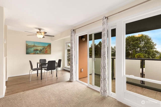 doorway to outside with ceiling fan, a baseboard heating unit, and light carpet