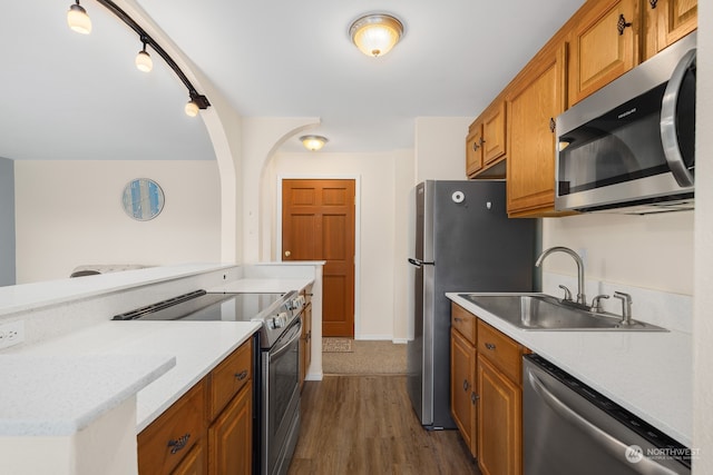 kitchen featuring rail lighting, sink, stainless steel appliances, and dark wood-type flooring