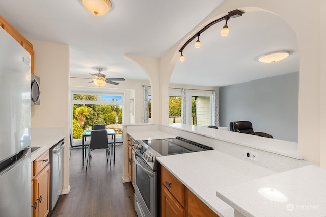 kitchen featuring dark hardwood / wood-style floors, rail lighting, stainless steel appliances, and a healthy amount of sunlight