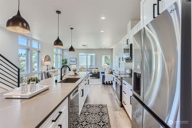 kitchen with appliances with stainless steel finishes, light hardwood / wood-style flooring, white cabinetry, and a wealth of natural light