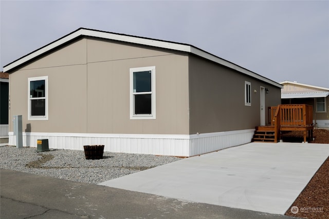 view of side of property featuring a wooden deck and a patio area