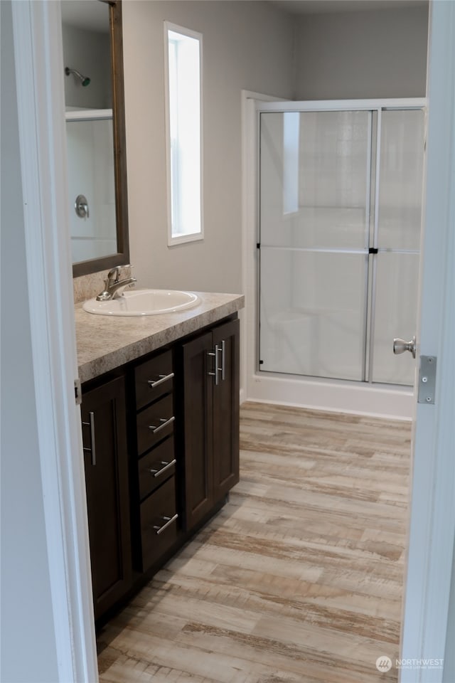 bathroom with vanity, a shower with shower door, and hardwood / wood-style flooring