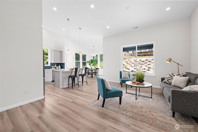 living area with light wood-style floors, a high ceiling, baseboards, and recessed lighting