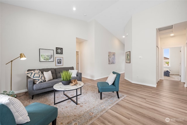 living room with high vaulted ceiling and light hardwood / wood-style floors