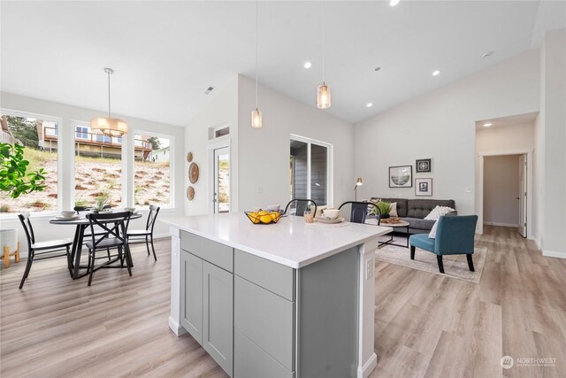 kitchen featuring an inviting chandelier, light hardwood / wood-style flooring, a kitchen island, hanging light fixtures, and gray cabinets