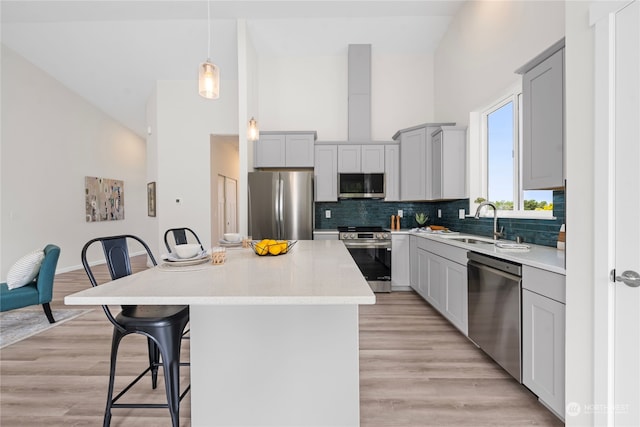 kitchen with a center island, high vaulted ceiling, light hardwood / wood-style floors, gray cabinetry, and stainless steel appliances