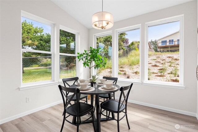 dining space with light wood-type flooring, lofted ceiling, and a healthy amount of sunlight