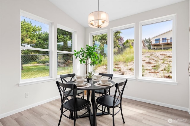 dining space with light wood finished floors, baseboards, and vaulted ceiling