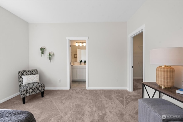 bedroom with a spacious closet, baseboards, ensuite bathroom, and light colored carpet