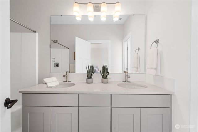 bathroom with visible vents, a sink, and double vanity