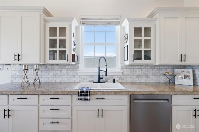 kitchen with backsplash, white cabinetry, stainless steel dishwasher, and sink