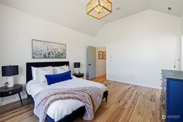 bedroom featuring light hardwood / wood-style flooring, lofted ceiling, and a notable chandelier