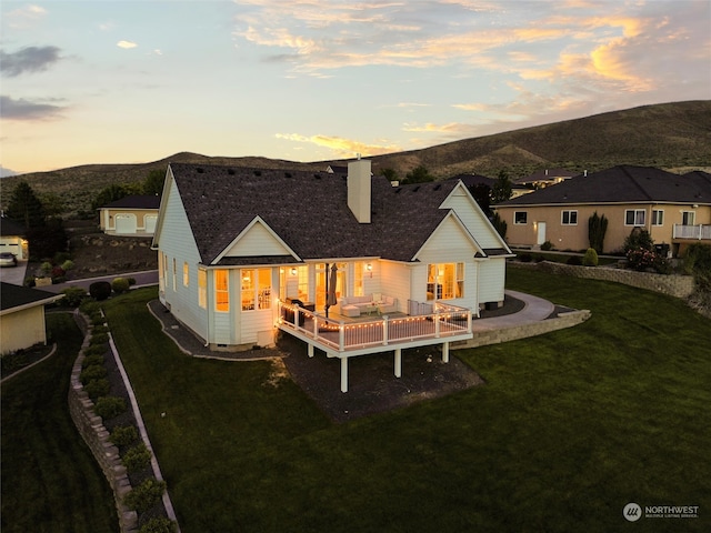 back house at dusk with a yard and a deck with mountain view