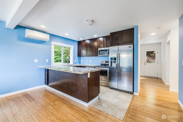 kitchen with light hardwood / wood-style floors, light stone counters, stainless steel appliances, sink, and a wall mounted AC