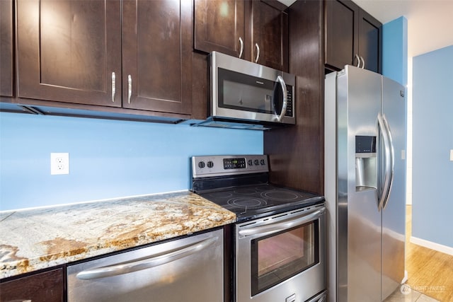 kitchen with light stone counters, light hardwood / wood-style floors, appliances with stainless steel finishes, and dark brown cabinetry