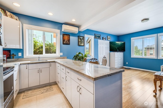4432 23rd Ave SW, Seattle, WA 98106 - kitchen featuring light stone counters, a peninsula, a wall unit AC, electric stove, and a sink