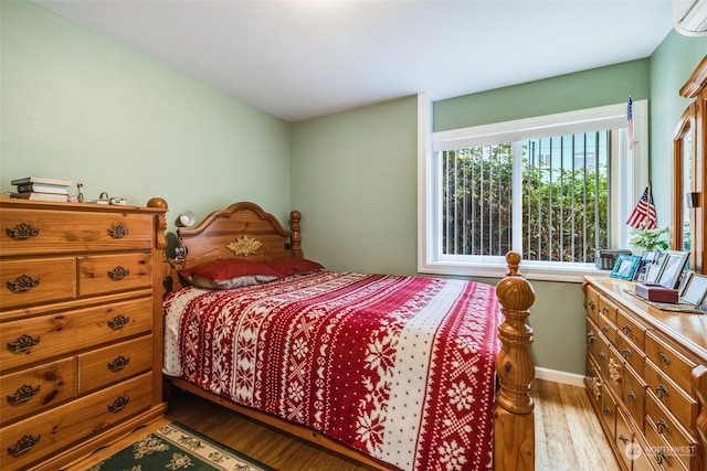 bedroom with a wall unit AC and light hardwood / wood-style floors