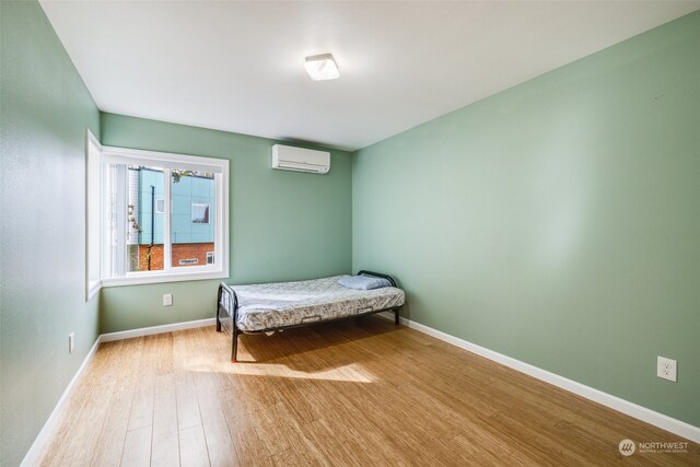 bedroom with wood-type flooring and an AC wall unit