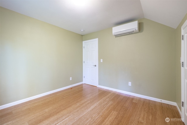 unfurnished room with lofted ceiling, light hardwood / wood-style floors, and a wall mounted AC