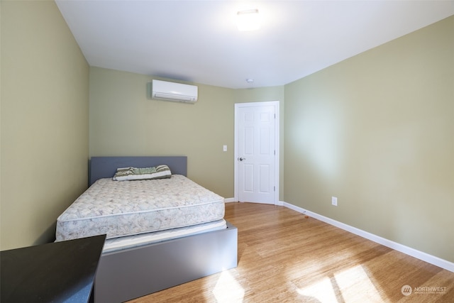 bedroom with light wood-type flooring and a wall mounted air conditioner