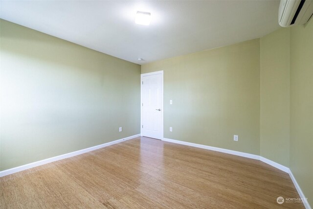 empty room featuring light hardwood / wood-style floors and a wall unit AC