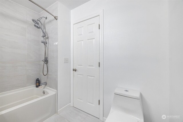 bathroom with tiled shower / bath combo and toilet