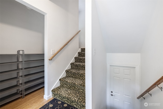 stairs with lofted ceiling and hardwood / wood-style flooring