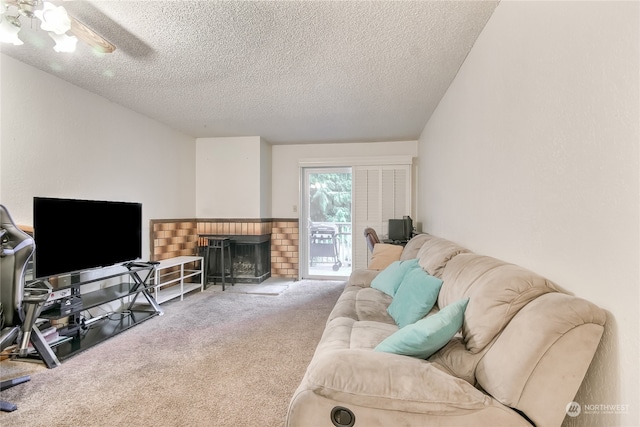 living room featuring carpet floors, a brick fireplace, ceiling fan, and a textured ceiling