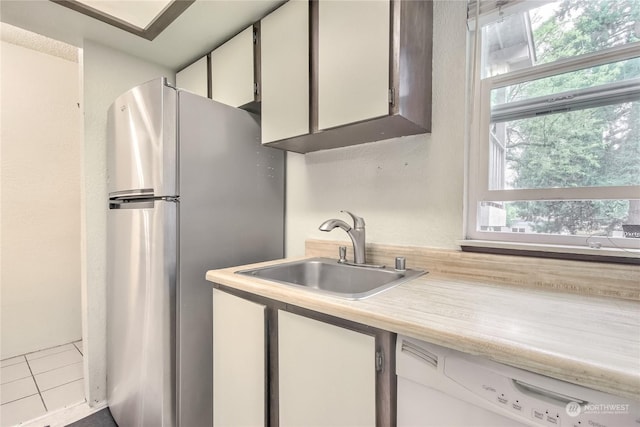 kitchen featuring freestanding refrigerator, light countertops, a sink, and dishwasher