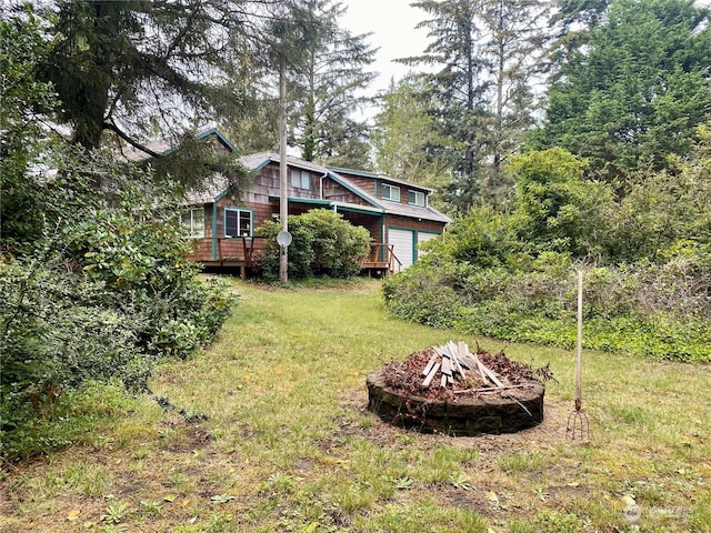 view of yard with a garage, an outdoor fire pit, and a deck