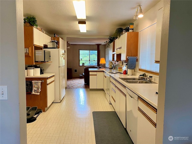 kitchen with white cabinets, white appliances, light countertops, and a sink