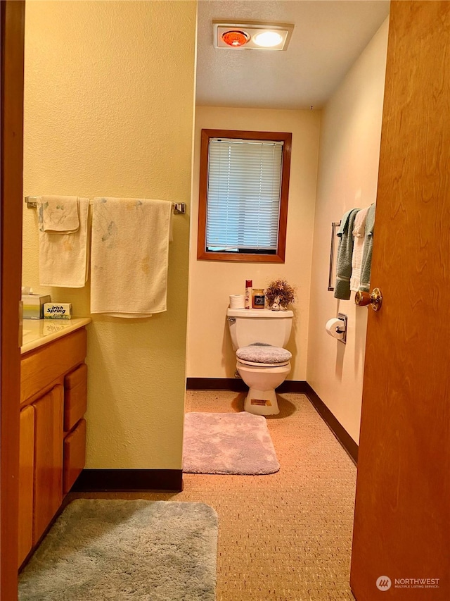 bathroom with toilet, baseboards, and vanity