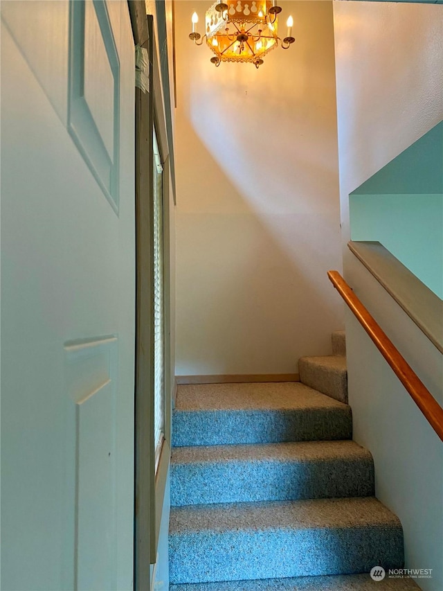 stairs with an inviting chandelier and baseboards