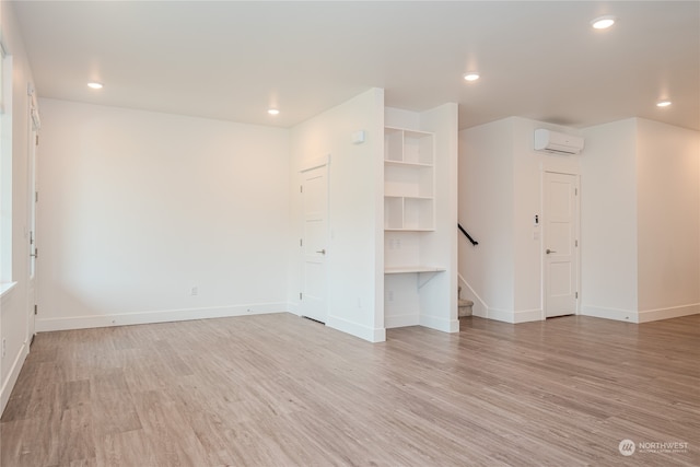 empty room with light wood-type flooring and a wall unit AC