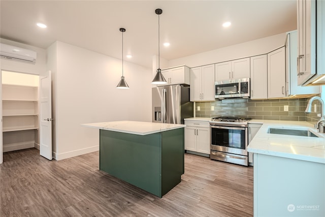 kitchen with a center island, stainless steel appliances, sink, white cabinetry, and a wall mounted AC