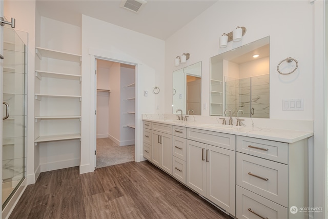 bathroom with walk in shower, vanity, and hardwood / wood-style floors